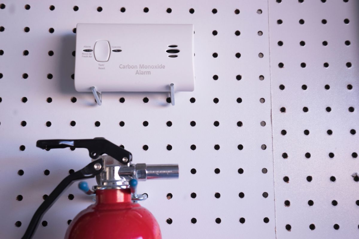 A fire extinguisher and smoke detector mounted on a wall, ensuring safety and fire prevention in the area.