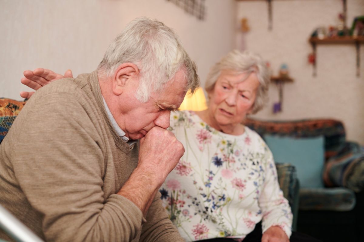 An older couple sitting together on a couch, sharing a moment of companionship and warmth.