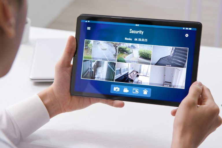 A man displays a tablet showing a security camera feed, highlighting surveillance technology in use.