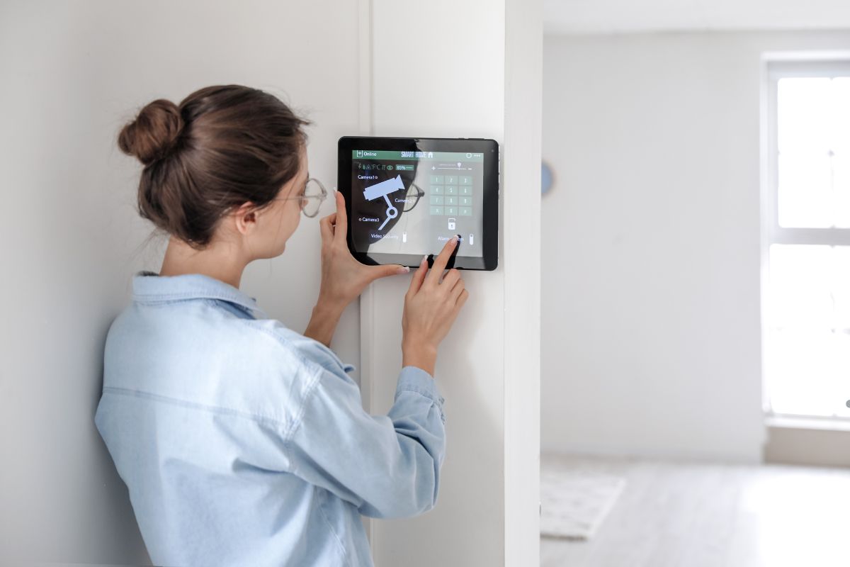A woman adjusts the thermostat using a tablet, demonstrating smart home technology in a modern living space.